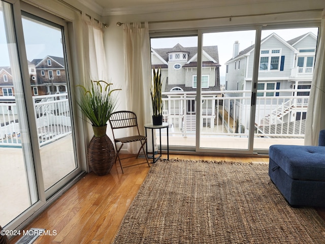 doorway to outside with a residential view, wood finished floors, visible vents, and crown molding