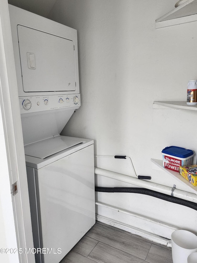laundry area with laundry area, wood finished floors, and stacked washer / drying machine