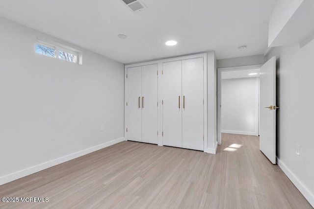 unfurnished bedroom featuring light wood finished floors, multiple closets, visible vents, and baseboards