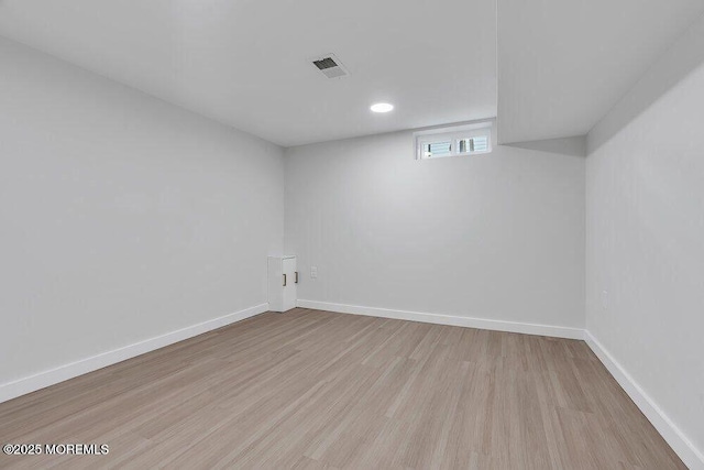 basement featuring wood finished floors, visible vents, and baseboards