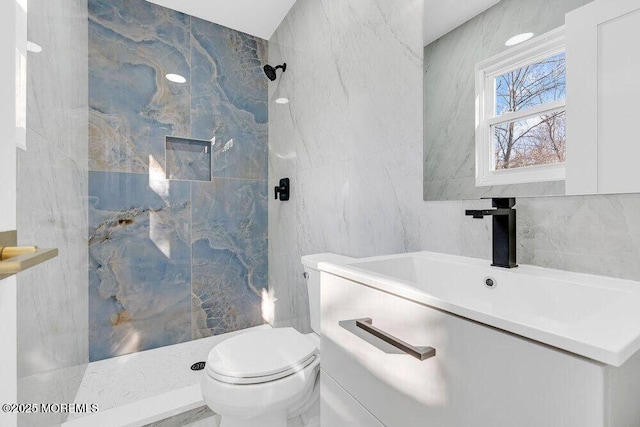 bathroom with toilet, tile walls, a marble finish shower, and vanity