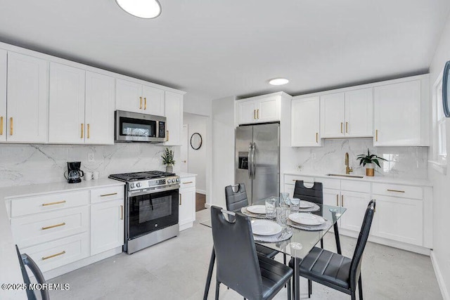 kitchen with stainless steel appliances, light countertops, white cabinetry, and a sink