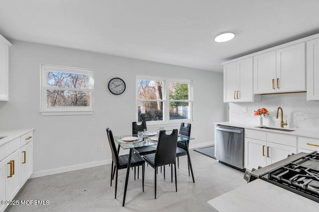 kitchen with dishwasher, tasteful backsplash, a sink, and white cabinetry