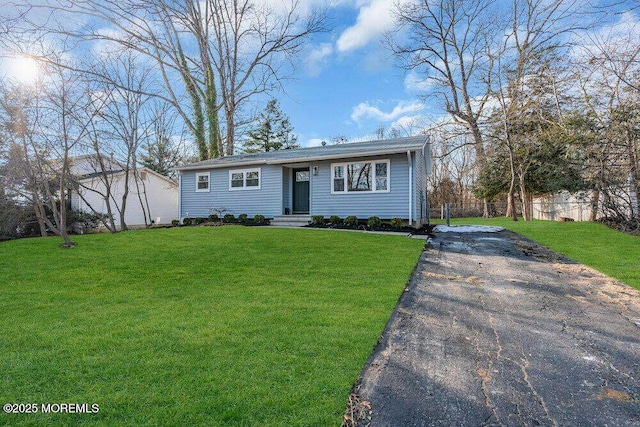 view of front of home with driveway, fence, and a front lawn