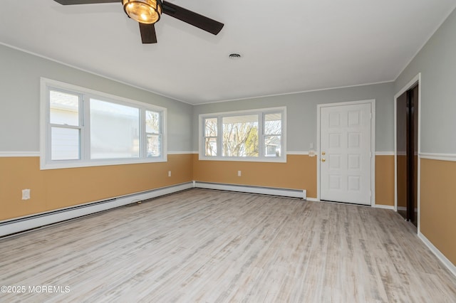 empty room with visible vents, wood finished floors, crown molding, a baseboard radiator, and baseboards