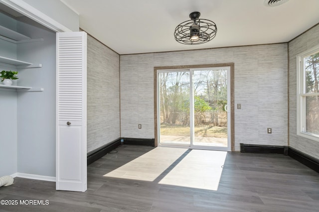 doorway with baseboards, wood finished floors, and a ceiling fan