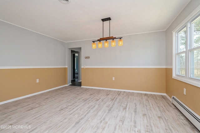 empty room featuring a baseboard radiator, baseboards, wood finished floors, and crown molding