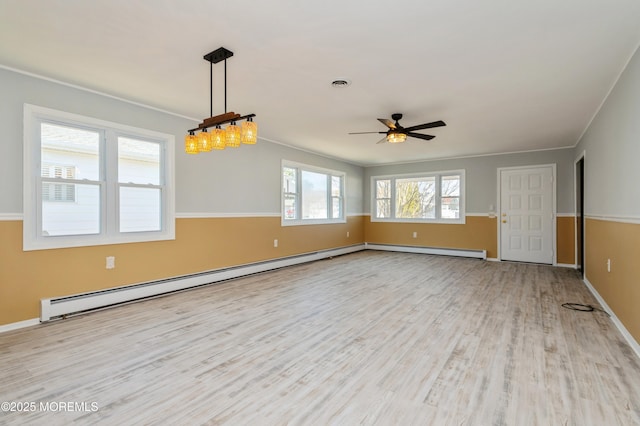 empty room featuring visible vents, wood finished floors, a baseboard heating unit, and ornamental molding