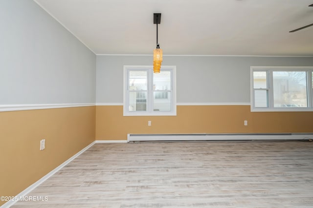 unfurnished room featuring baseboards, baseboard heating, wood finished floors, and ornamental molding