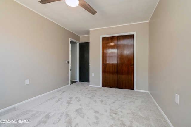 unfurnished bedroom featuring ceiling fan, carpet, baseboards, ornamental molding, and a closet