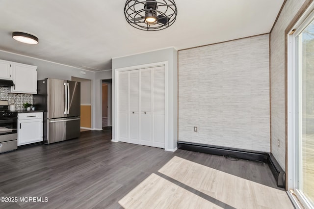 kitchen featuring under cabinet range hood, dark countertops, white cabinetry, stainless steel appliances, and dark wood-style flooring