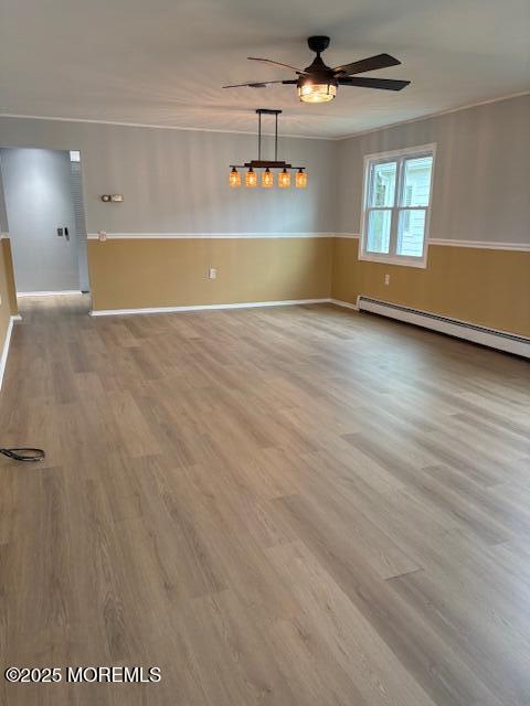 177 Freeport Blvd, Toms River, NJ 08757 - empty room featuring a ceiling fan, wood finished floors, wainscoting, a baseboard radiator, and ornamental molding