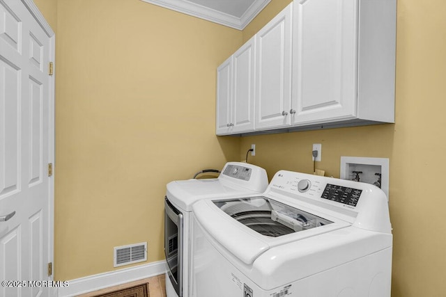 clothes washing area featuring visible vents, baseboards, cabinet space, washer and dryer, and crown molding