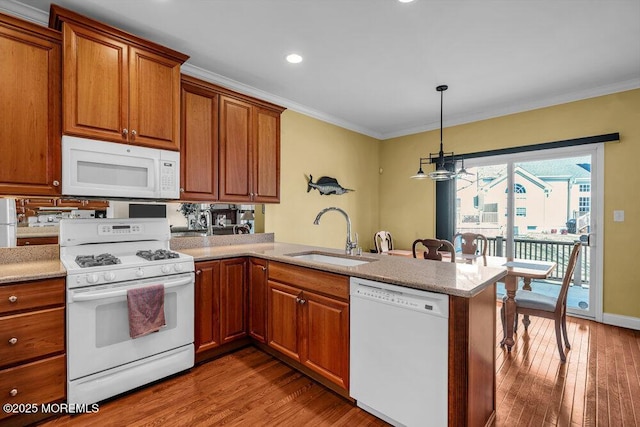 kitchen with a sink, white appliances, a peninsula, and ornamental molding