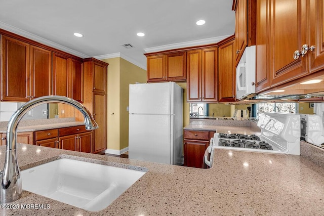 kitchen with light stone counters, ornamental molding, white appliances, and a sink