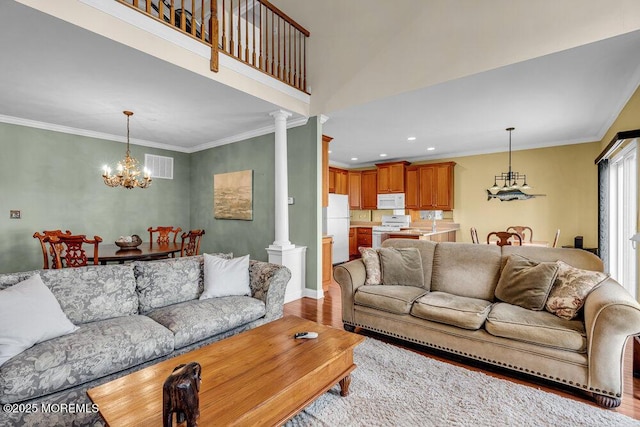 living area featuring visible vents, an inviting chandelier, wood finished floors, and crown molding