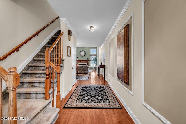 interior space featuring stairway, wood finished floors, baseboards, and ornamental molding