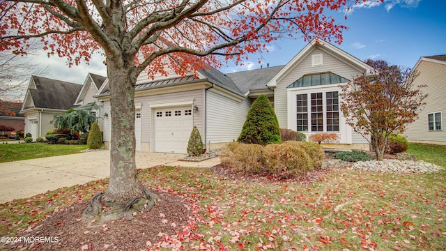 view of front of house with an attached garage, a standing seam roof, metal roof, and concrete driveway