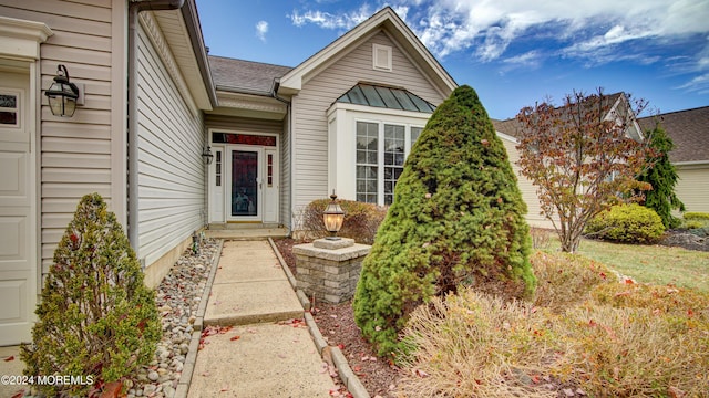 doorway to property featuring a garage, metal roof, a standing seam roof, and roof with shingles