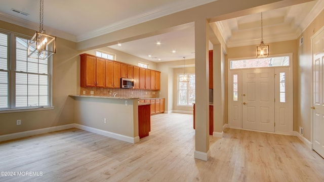 interior space with crown molding, visible vents, a chandelier, light wood-type flooring, and baseboards