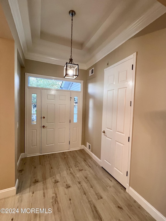 entryway featuring light wood finished floors, baseboards, and a tray ceiling