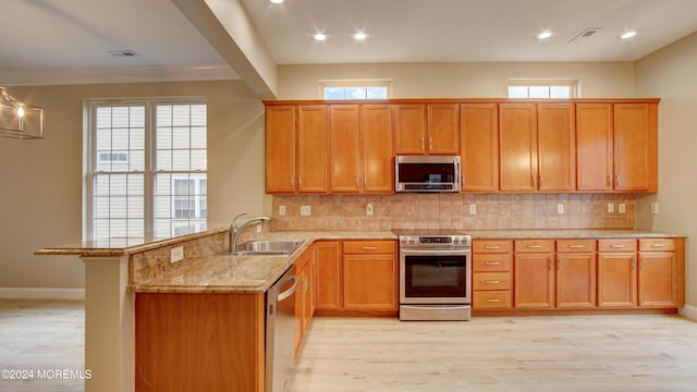 kitchen featuring visible vents, appliances with stainless steel finishes, a peninsula, a sink, and backsplash