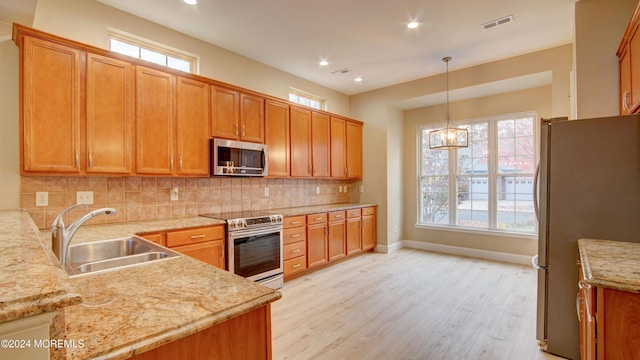 kitchen with visible vents, backsplash, appliances with stainless steel finishes, a sink, and light wood-type flooring