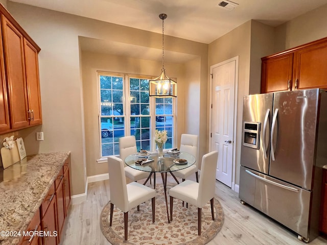 dining area featuring light wood-type flooring, an inviting chandelier, visible vents, and baseboards