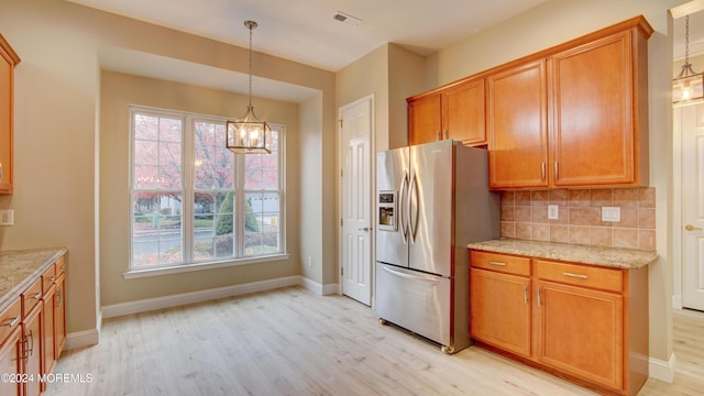 kitchen featuring tasteful backsplash, light wood-type flooring, brown cabinetry, and stainless steel fridge