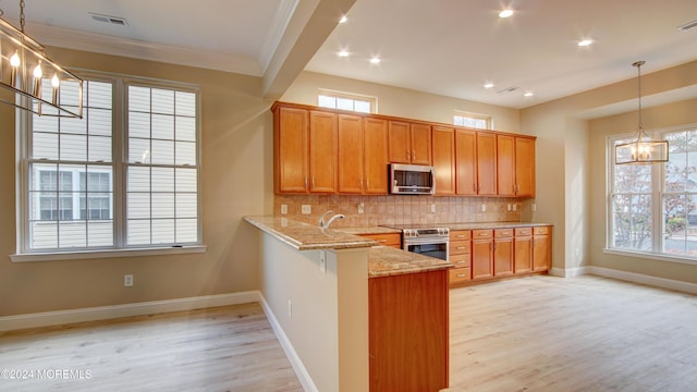 kitchen with light wood-style flooring, light stone countertops, an inviting chandelier, stainless steel appliances, and backsplash