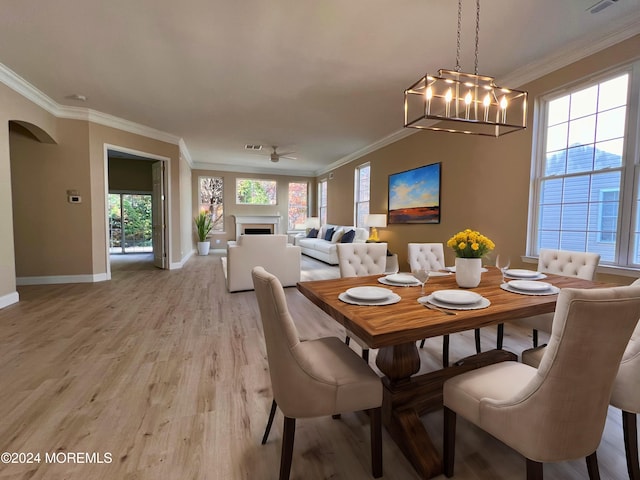 dining area featuring baseboards, ornamental molding, an inviting chandelier, light wood-style floors, and a fireplace