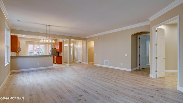 unfurnished living room with arched walkways, visible vents, ornamental molding, light wood-type flooring, and baseboards