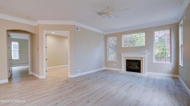 unfurnished living room featuring ornamental molding, arched walkways, and visible vents