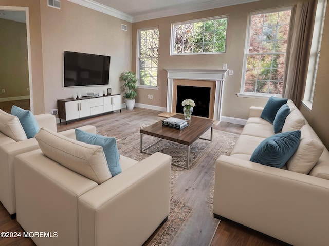 living room featuring baseboards, visible vents, ornamental molding, wood finished floors, and a fireplace