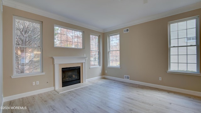 unfurnished living room featuring a high end fireplace, visible vents, crown molding, and wood finished floors