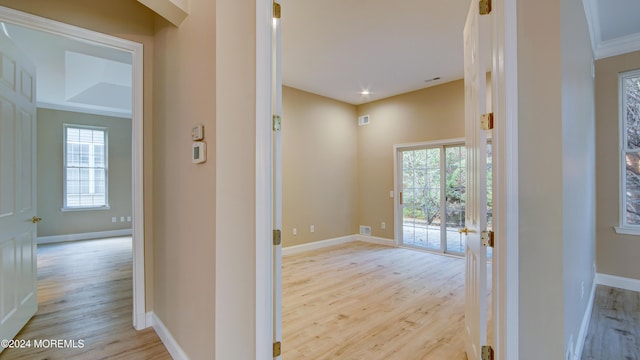 hallway with visible vents, light wood-style flooring, and baseboards