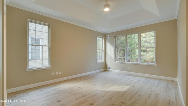 spare room with crown molding, a tray ceiling, wood finished floors, and baseboards