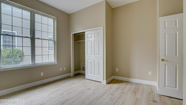 unfurnished bedroom with light wood finished floors, a closet, and baseboards