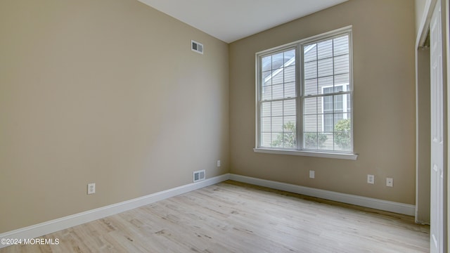 empty room featuring baseboards, visible vents, and wood finished floors