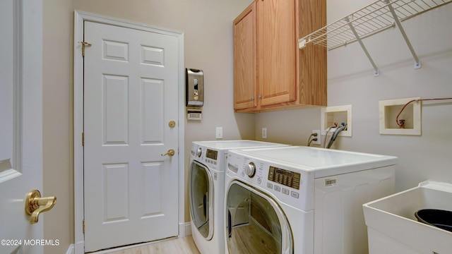 laundry area with light wood-style flooring, a sink, cabinet space, and washer and dryer