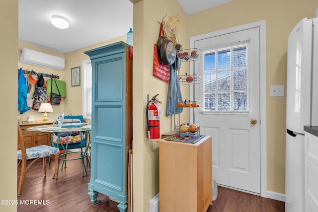 interior space featuring a wall unit AC, a healthy amount of sunlight, baseboards, and dark wood finished floors