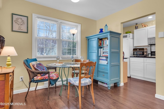 dining room with dark wood-type flooring, baseboard heating, and baseboards