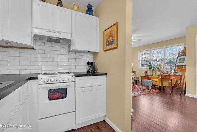 kitchen featuring white range with electric cooktop, dark countertops, backsplash, and under cabinet range hood