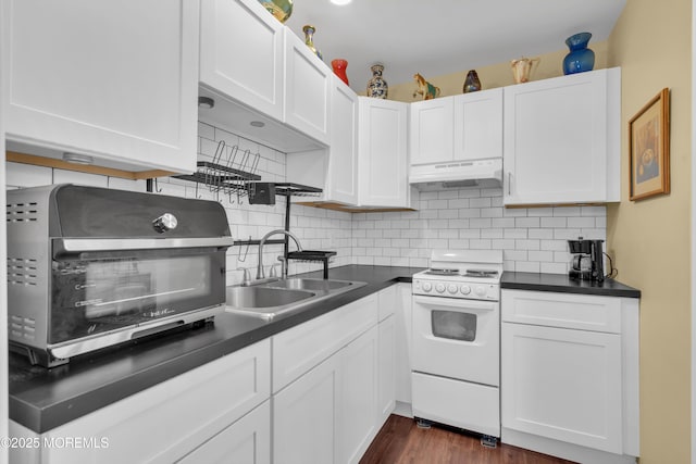 kitchen with dark countertops, a sink, under cabinet range hood, and white electric range oven