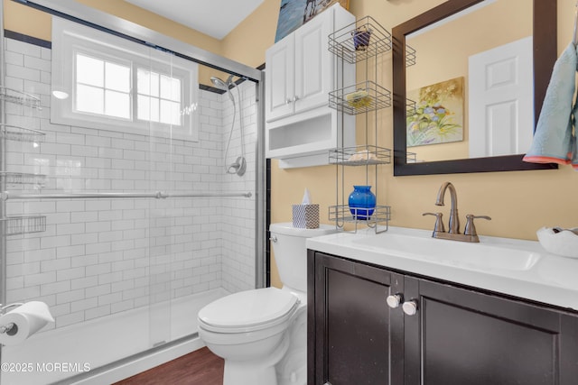 full bath featuring wood finished floors, a shower stall, toilet, and vanity