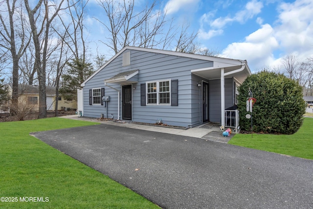 bungalow featuring aphalt driveway and a front lawn