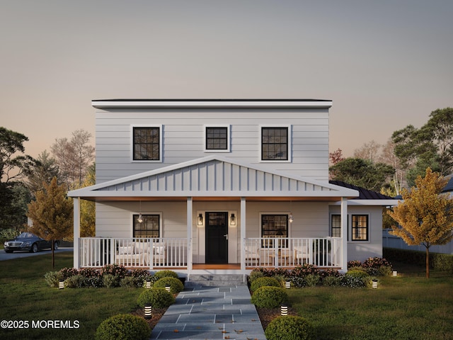 view of front facade with a standing seam roof, a porch, a yard, and metal roof