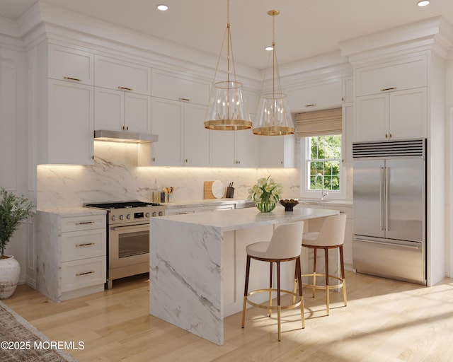 kitchen with under cabinet range hood, white cabinets, appliances with stainless steel finishes, and a center island