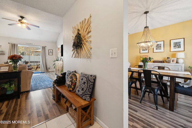 interior space with wood finished floors, baseboards, vaulted ceiling, a textured ceiling, and ceiling fan with notable chandelier