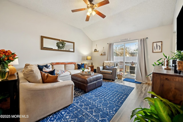 living area with a textured ceiling, wood finished floors, a ceiling fan, and vaulted ceiling